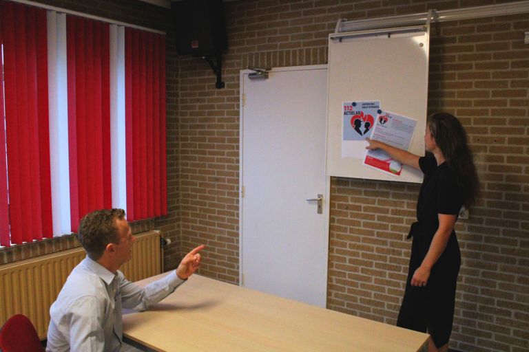 Een man en een vrouw presenteren informatie in een vergaderruimte.