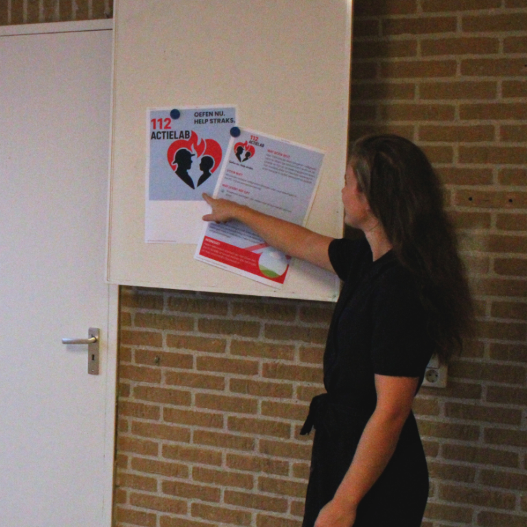 Een vrouw wijst naar informatie op een muur.