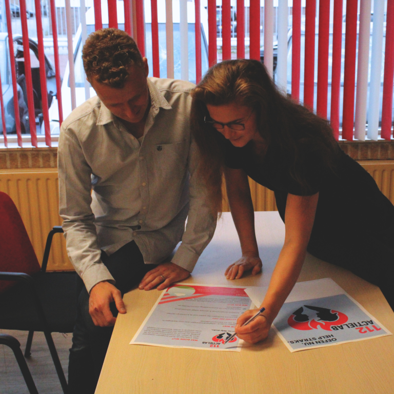 Twee mensen ondertekenen documenten aan een tafel en  brainstormen